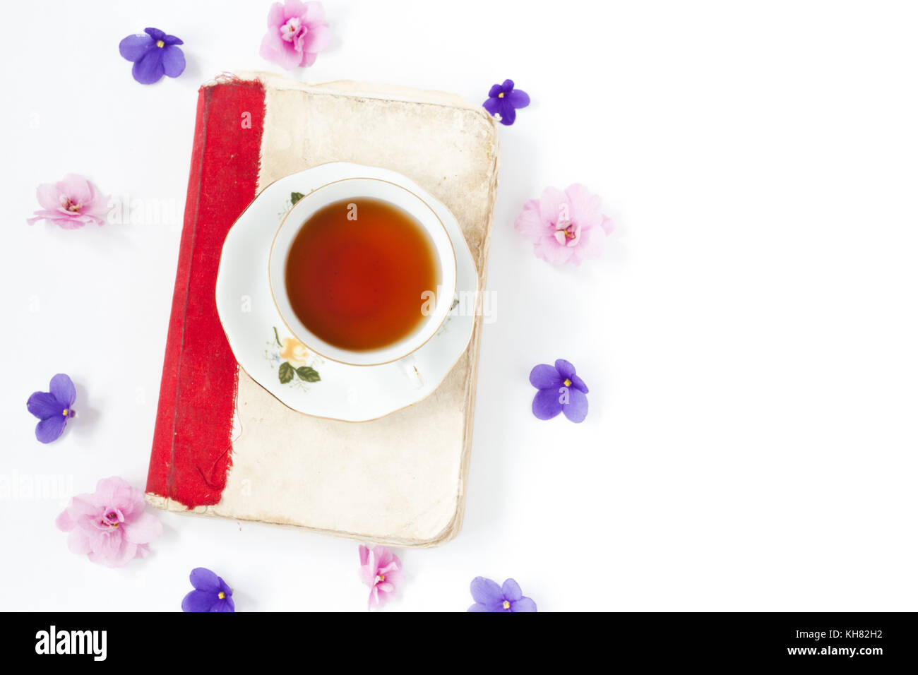 Altes Buch mit Tee oder Kaffee mit Blumen auf weißem Hintergrund Stockfoto