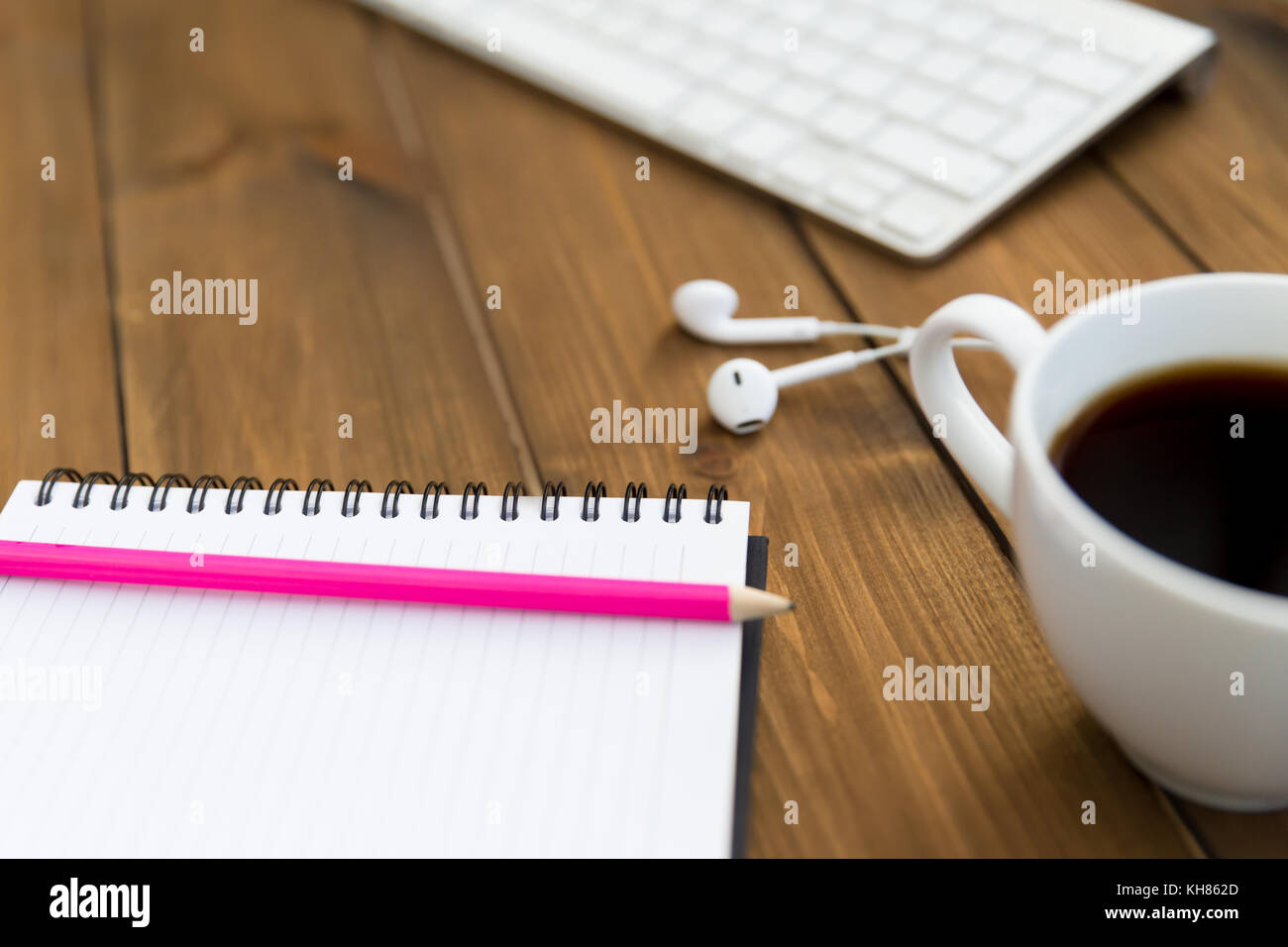 Computer Tastatur Notizblock bleistift Musik Ohrhörer und Kaffee auf Holz Schreibtisch Arbeitsbereich Stockfoto