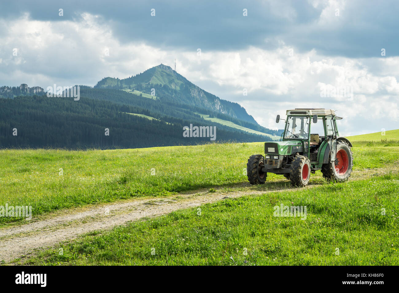Alten Traktor auf Wiese. schönem Blick auf die Berge in den Alpen Stockfoto