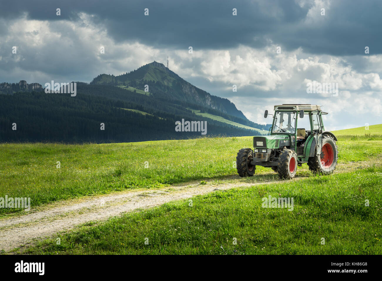 Alten Traktor auf Wiese. schönem Blick auf die Berge in den Alpen Stockfoto