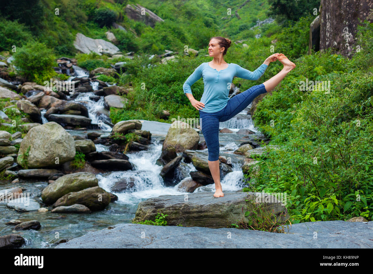 Frau tut Ashtanga Vinyasa Yoga Asana im Freien am Wasserfall Stockfoto