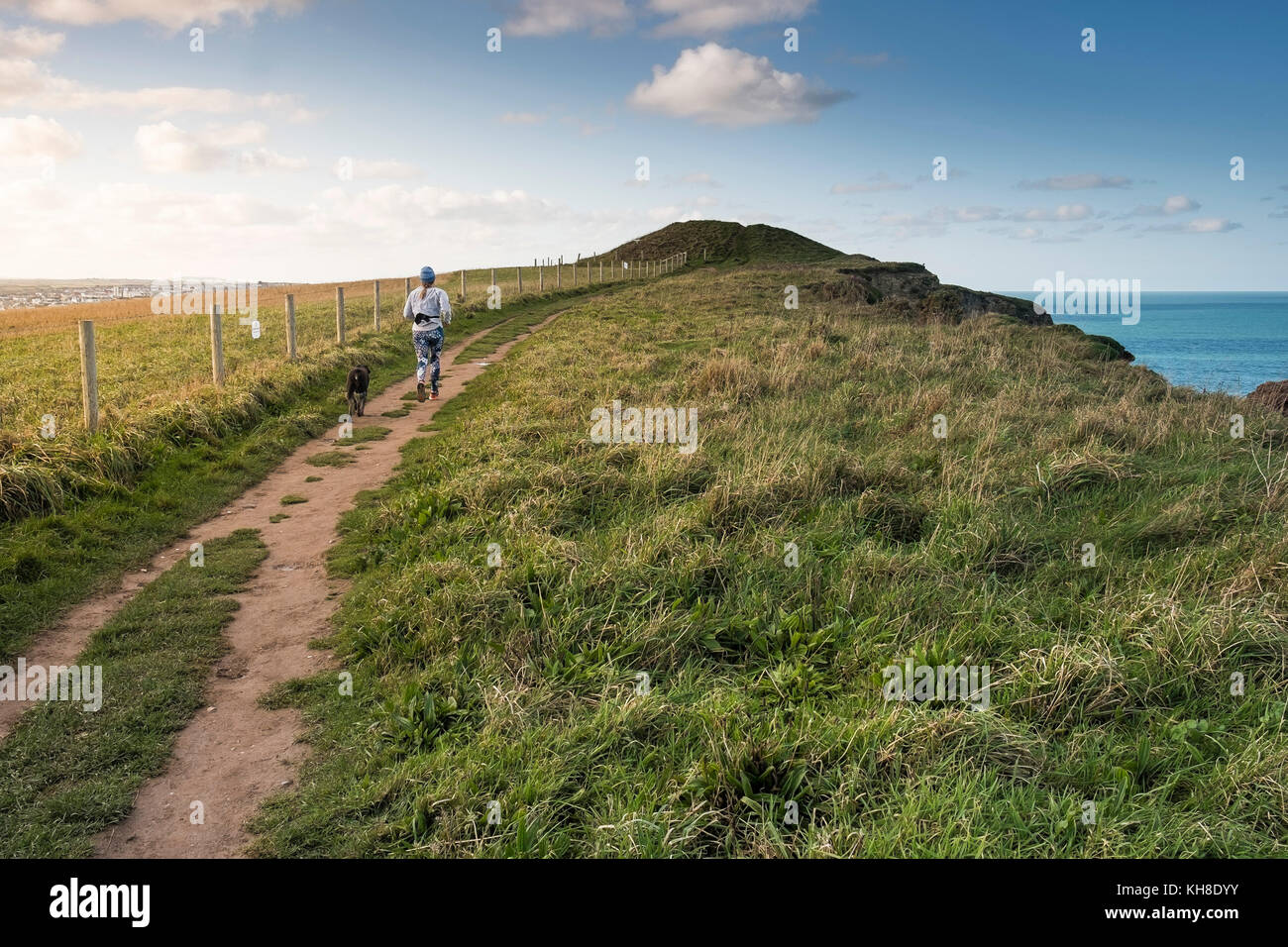 Eine Frau und ihr Hund entlang des South West Coast Path in Newquay Cornwall im Vereinigten Königreich ausgeführt wird. Stockfoto