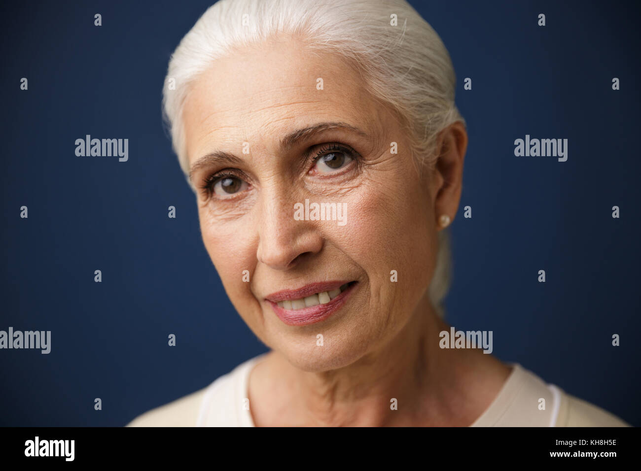 Close-up Portrait von lächelnden Reife kaukasische Frau, Kamera, auf dunkelblauem Hintergrund Stockfoto