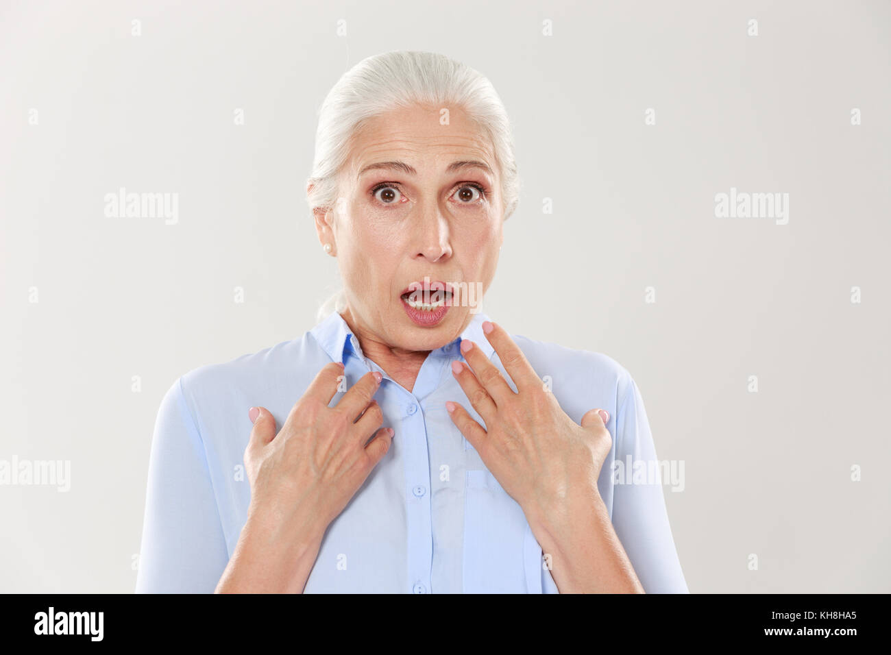 Close-up Portrait von schockiert reife Frau im blauen Hemd, lookink an Kamera, auf weißem Hintergrund Stockfoto