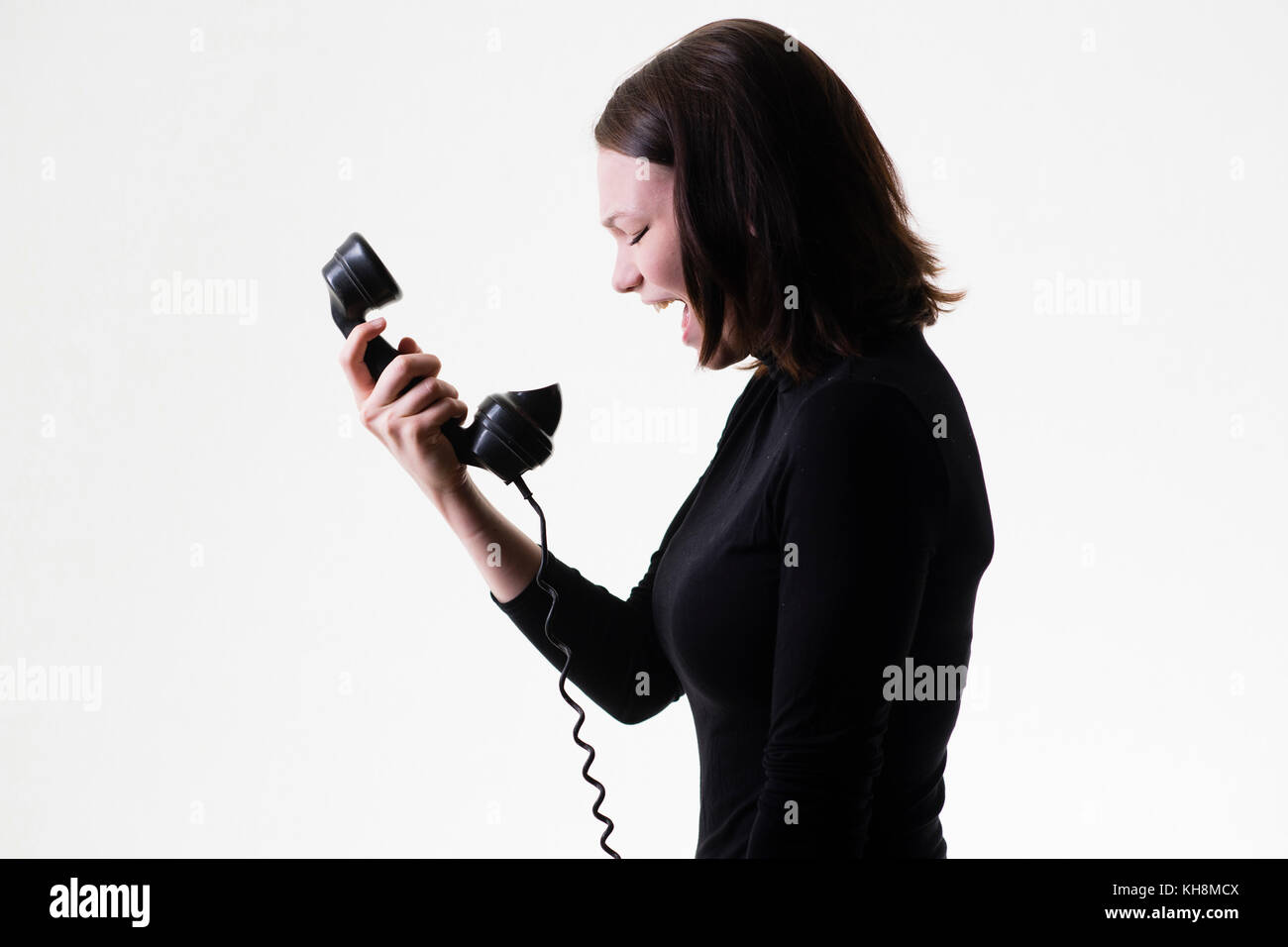 Beziehung Trennung: Ein wütend Wütende junge Braunhaarige kaukasischen teenage Mädchen schreien das Telefon, halten einen altmodischen schwarzen Bakelit Telefon Empfänger Stockfoto