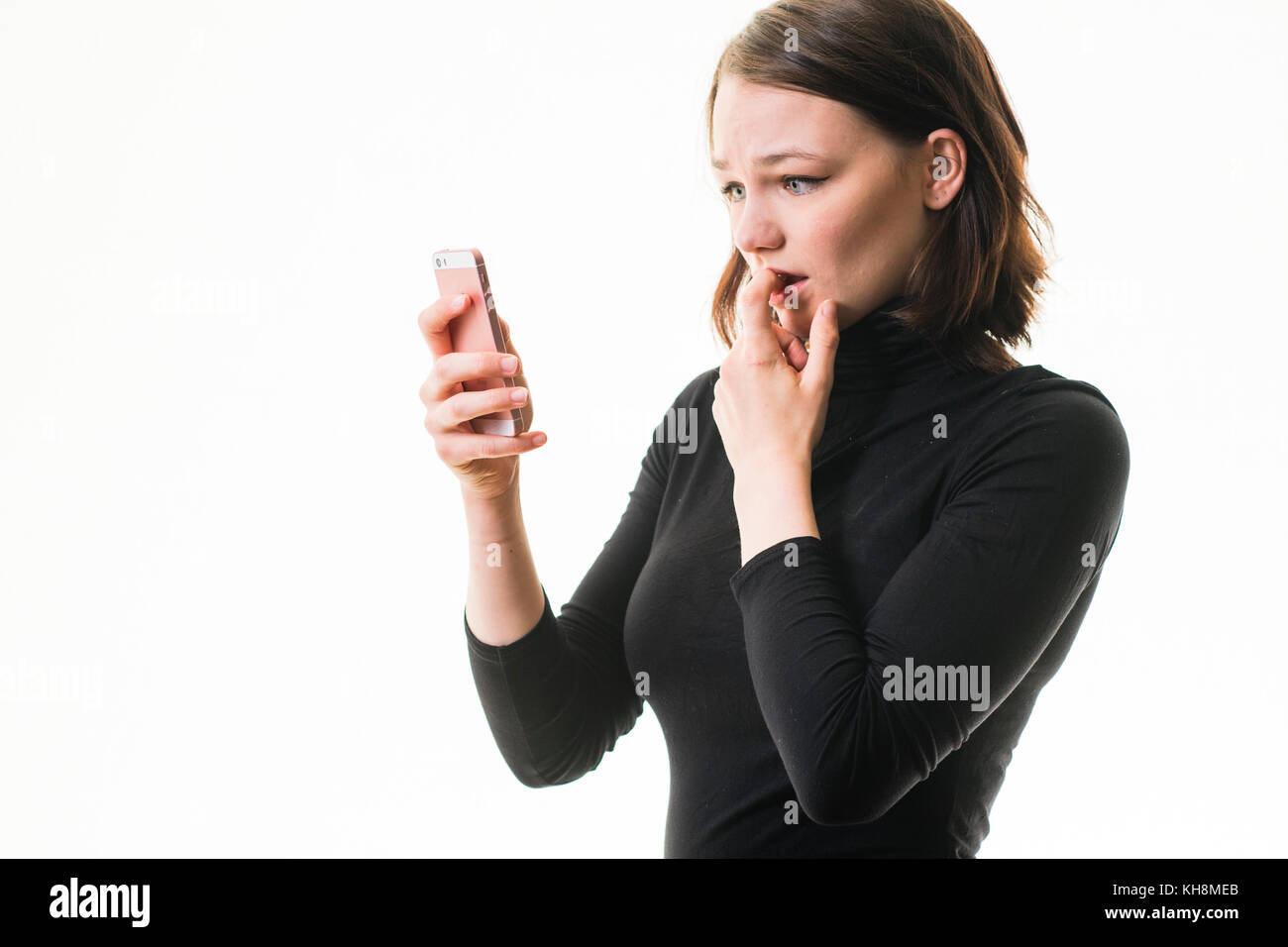 Hacking und Cyber Mobbing: Eine junge Braunhaarige kaukasischen teenage Mädchen auf ihrem Mobiltelefon, Smartphone, Handy, besorgt suchen, verwirrt, betroffen ist, durch den Inhalt der Nachricht, die Sie sehen, Großbritannien Stockfoto