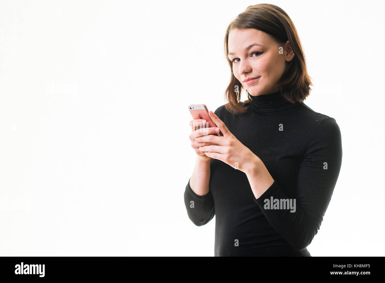 Eine junge Braunhaarige kaukasischen Jugendmädchen Messaging sms auf ihrem Handy, Smartphone, Handy, Stockfoto