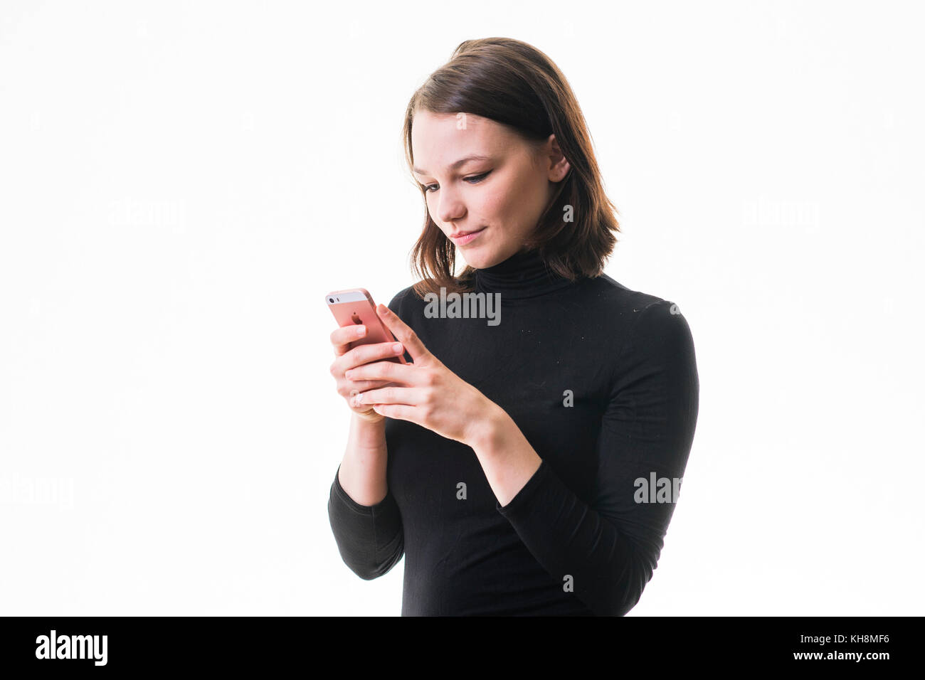 Eine junge Braunhaarige kaukasischen Jugendmädchen Messaging sms auf ihrem Handy, Smartphone, Handy, Stockfoto