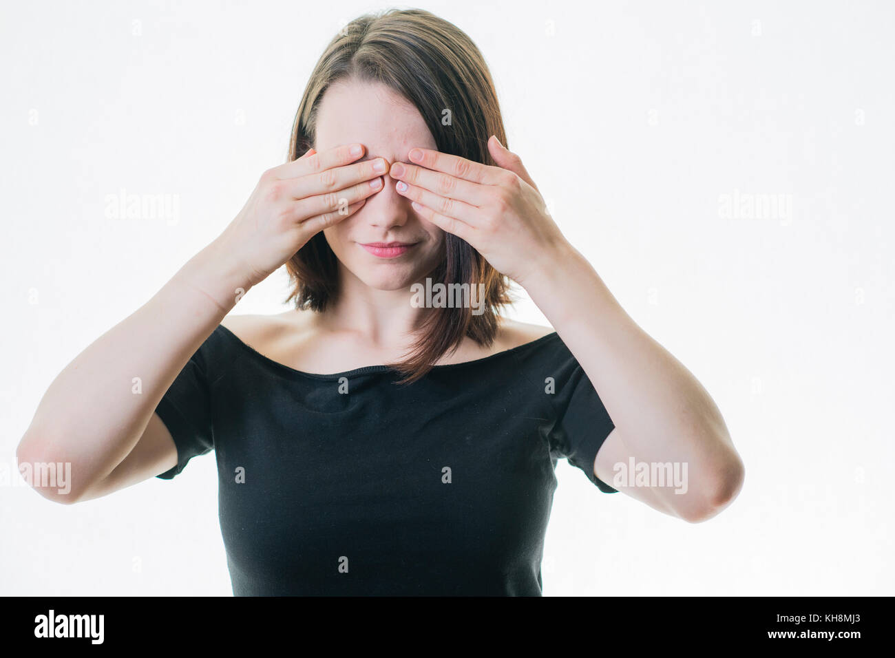 In Denial: Ein junges braunhaariges kaukasisches Teenager-Mädchen bedeckt beide Augen mit ihren Händen Stockfoto