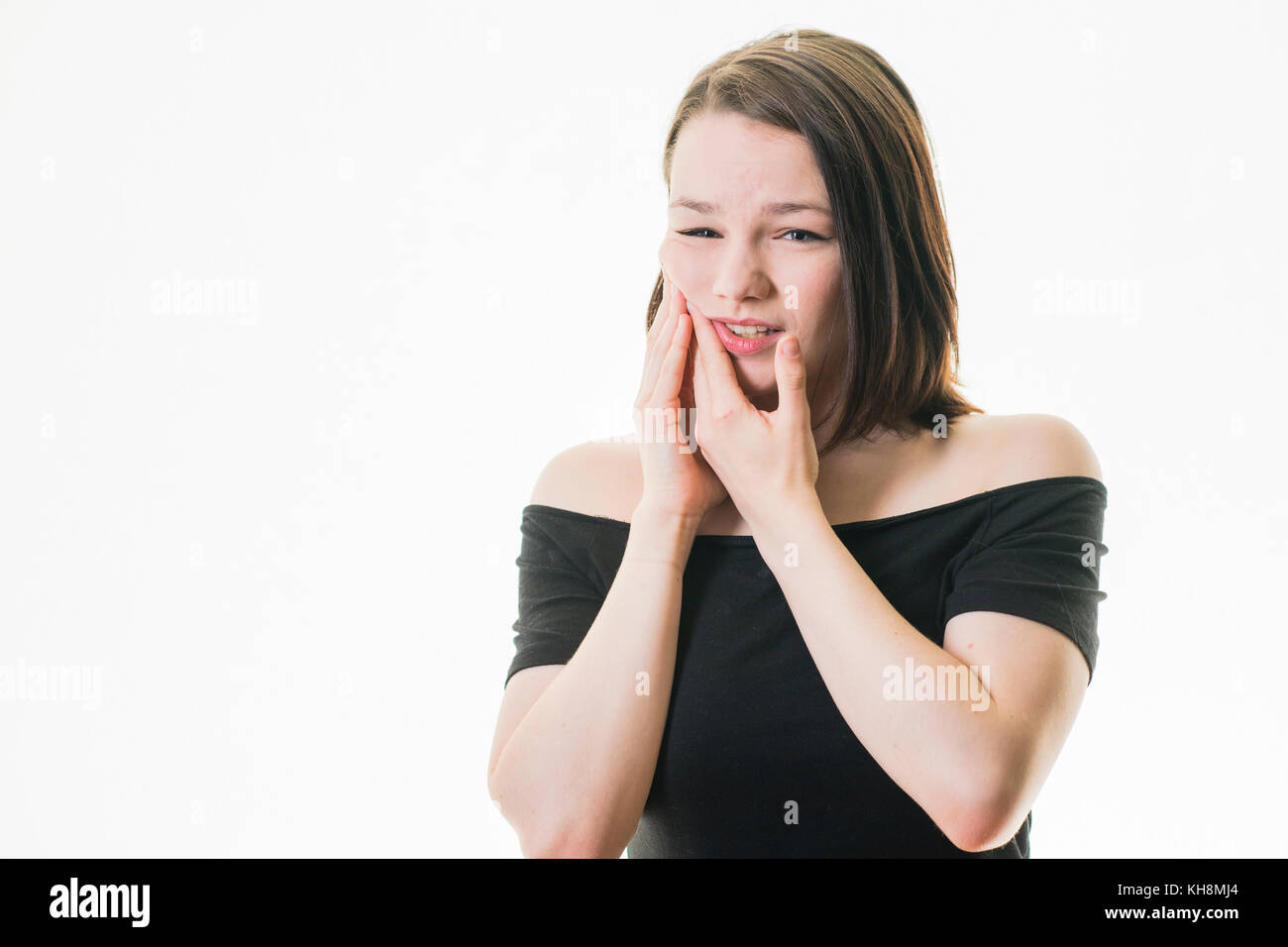 Karies und Zahnfleischerkrankungen in Großbritannien: Eine junge Braunhaarige kaukasischen Jugendmädchen Zahnschmerzen leiden, ihre Wange rieb mit der Hand Schmerzlinderung zu erhalten Stockfoto