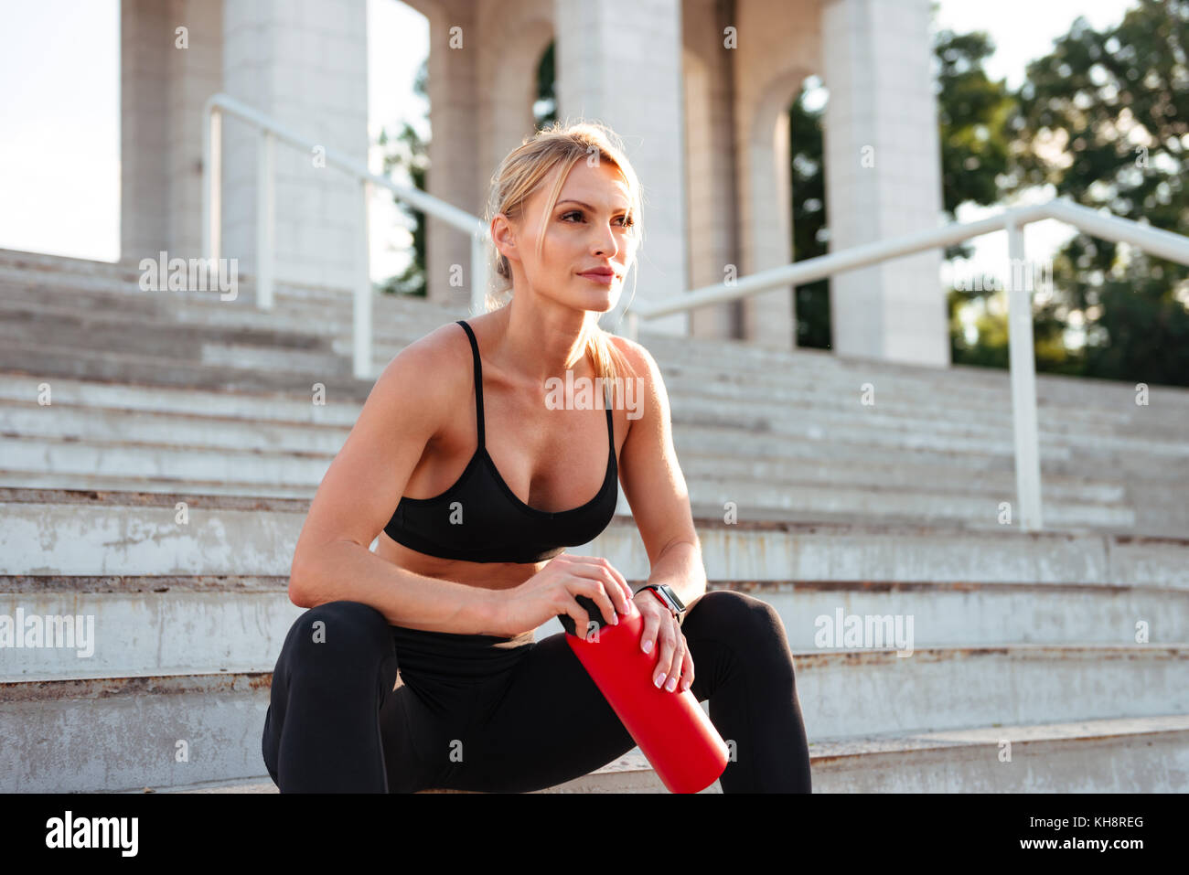 Bild der schönen starken jungen Sport Frau sitzt auf der Treppe Trinkwasser im Freien. Neben der Suche. Stockfoto
