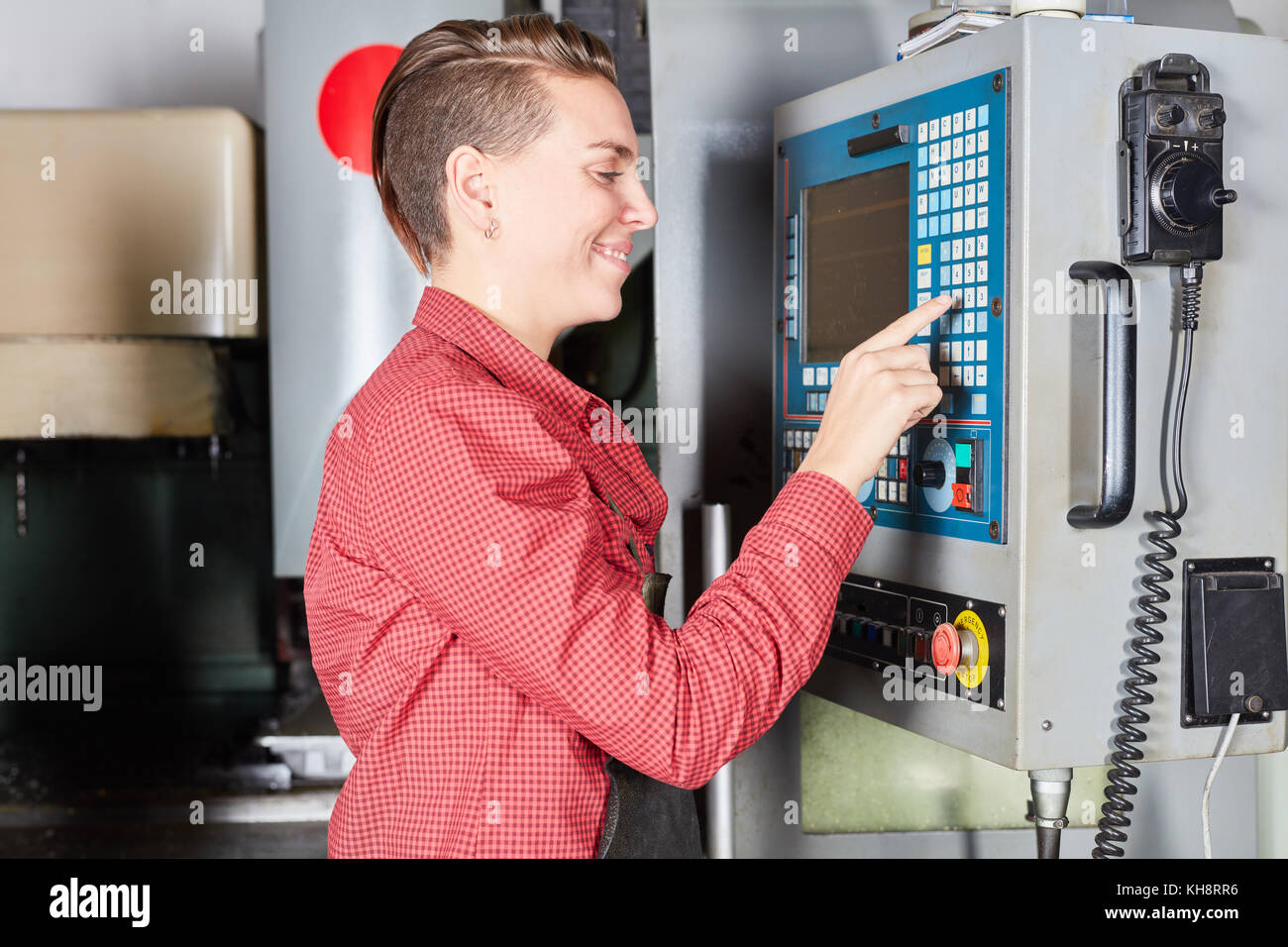 Junge Frau als Arbeitnehmer mit CNC-Maschine in der Metallurgie Factory Stockfoto Junge Frau als Arbeitnehmer mit CNC-Maschine in der Metallurgie Factory Stockfoto