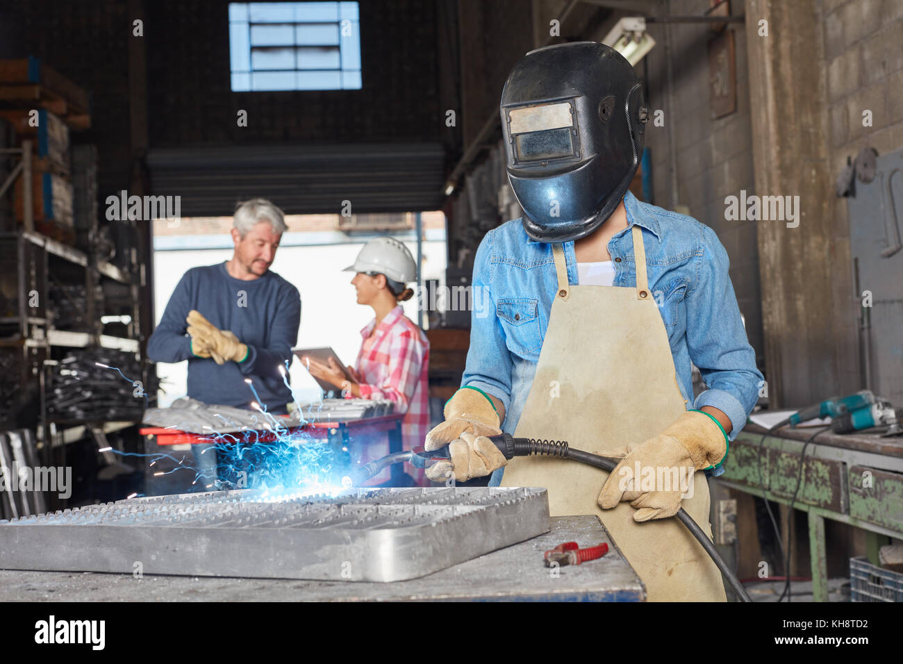 Schweißen Sie Arbeitnehmer oder Arbeiter mit Schutzkleidung in der Werkstatt Stockfoto