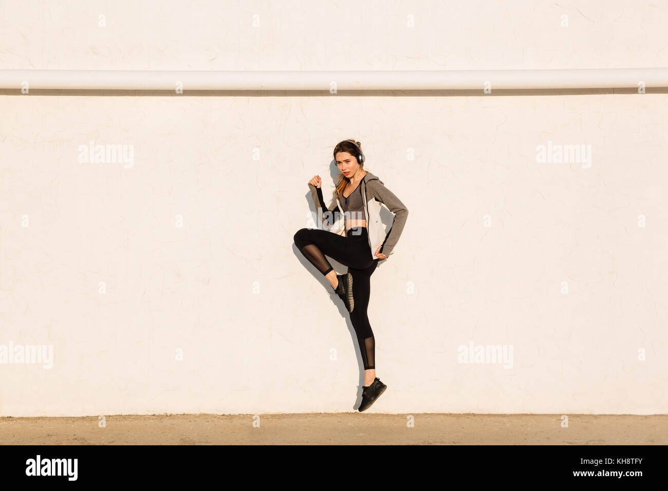 Volle Länge Foto von jungen Sport Frau in der Nähe von weißen Wand springen Stockfoto