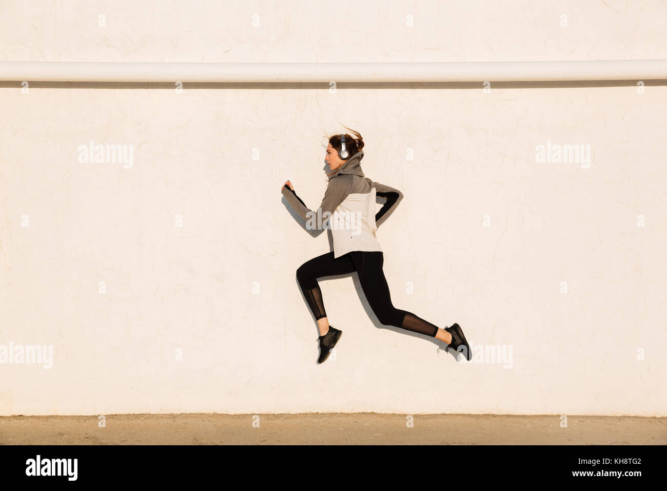 Volle Länge Foto der jungen Frau im Sport Fitness Verschleiß springen in der Nähe von weißen Wand Stockfoto