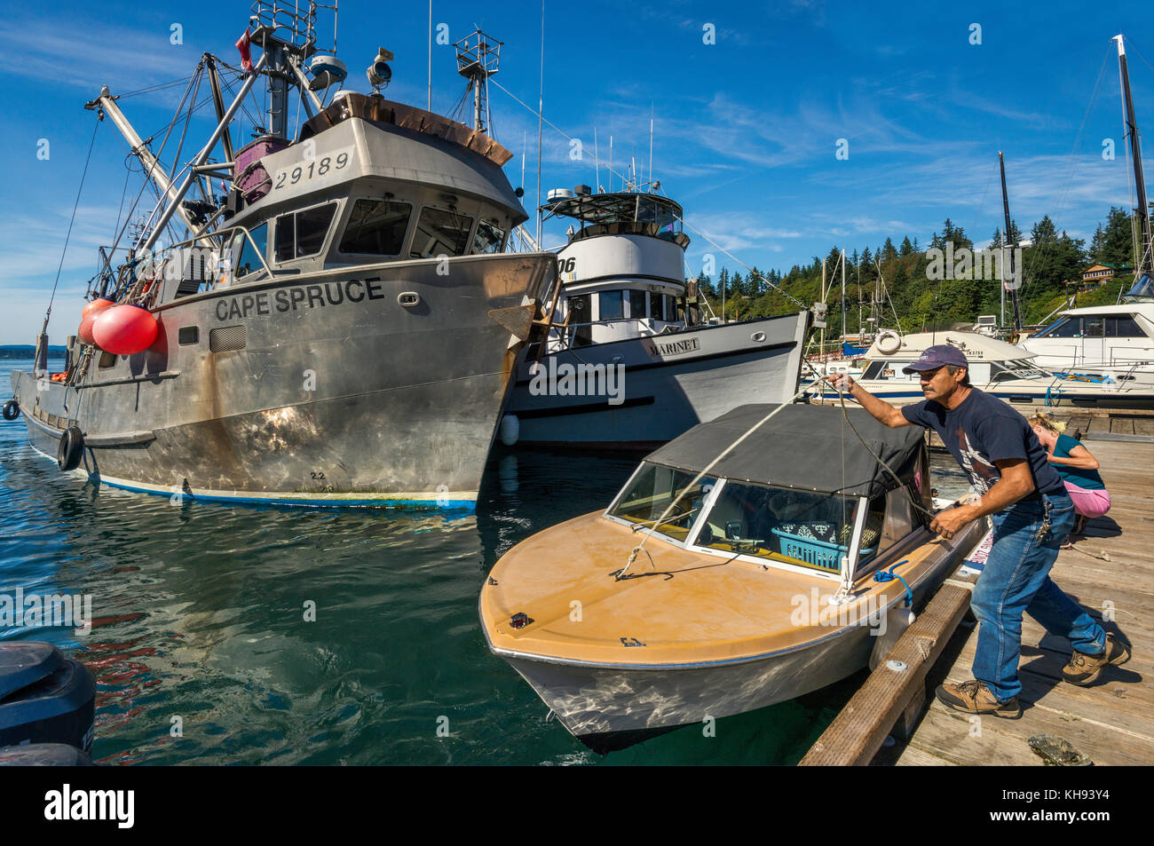 Frau, die Boot auf dem Steg bindet, Fischerboote, die am Yachthafen in Quathiaski Cove auf Quadra Island, Vancouver Island Area, British Columbia, Kanada geangelt sind Stockfoto