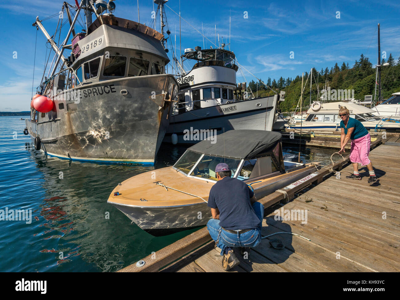 Mann und Frau binden Boot auf dem Steg, Fischerboote, die am Yachthafen in Quathiaski Cove auf Quadra Island, Vancouver Island, British Columbia, Angelehnt sind, Können Stockfoto