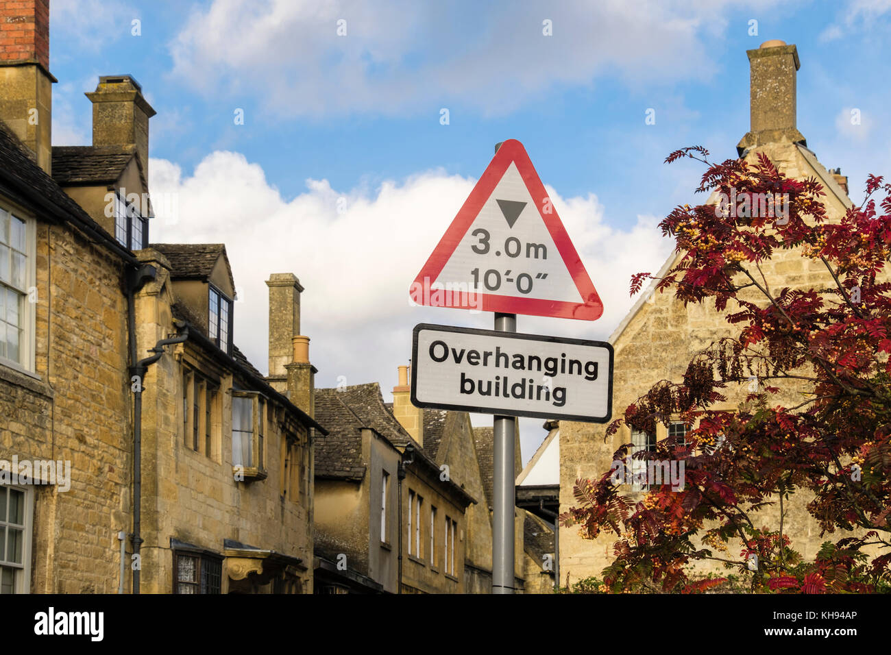 Ungewöhnliche Warnschild über überhängenden alte Cotswold Gebäude aus Stein auf schmalen Straße in Cotswolds Dorf. Tetbury Gloucestershire England Großbritannien Stockfoto