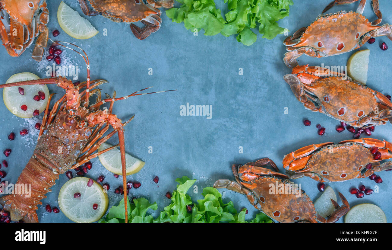 Essen Rahmen mit Krustentieren. Hummer, Krabben, Zitrone und Granatapfel auf Hintergrund Stockfoto