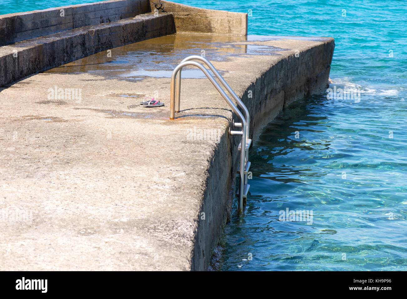 Rosa Hausschuhe auf dem Pier in der Nähe des Meeres Stockfoto