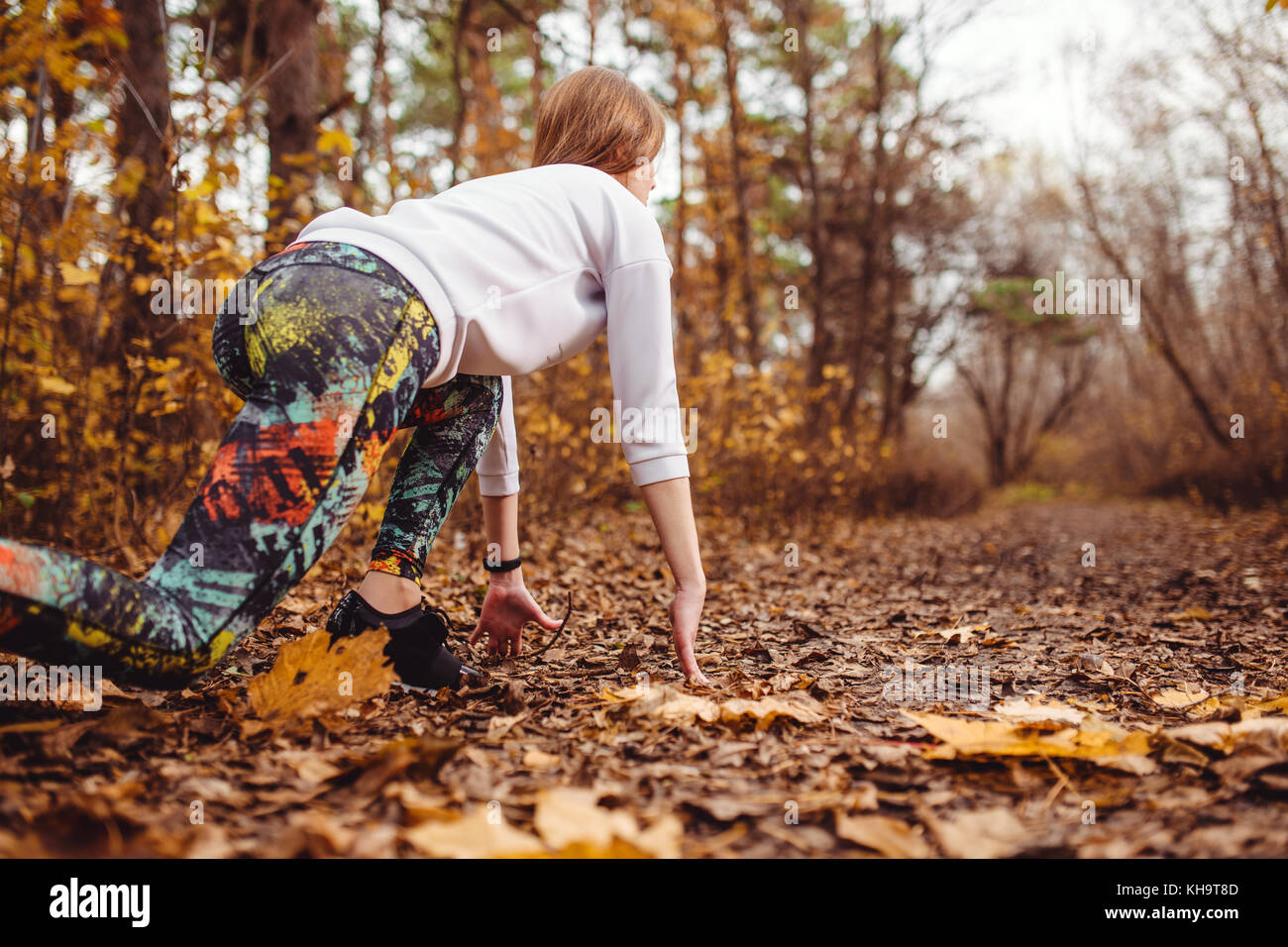 Concentrared junge sportliche Frau, die bereit ist, im Freien im Herbst Park zu laufen. Stockfoto