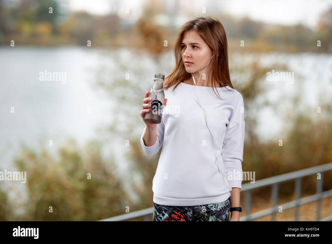 Junge Fitness Mädchen mit einer Flasche Wasser stehend Outdoor im City Park. Stockfoto