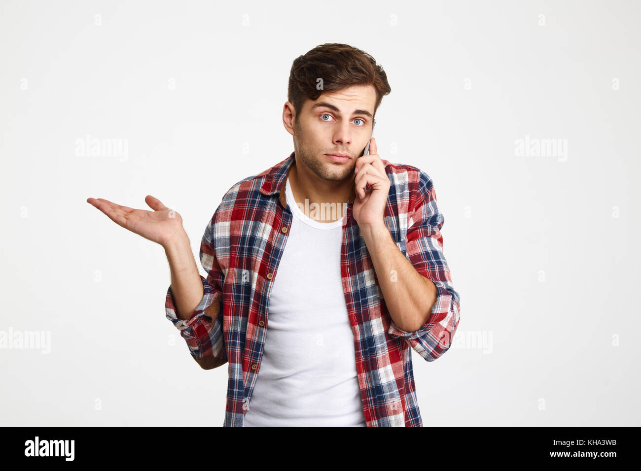 Porträt eines verwirrten verwirrten Mann Gespräch am Handy auf weißem Hintergrund Stockfoto