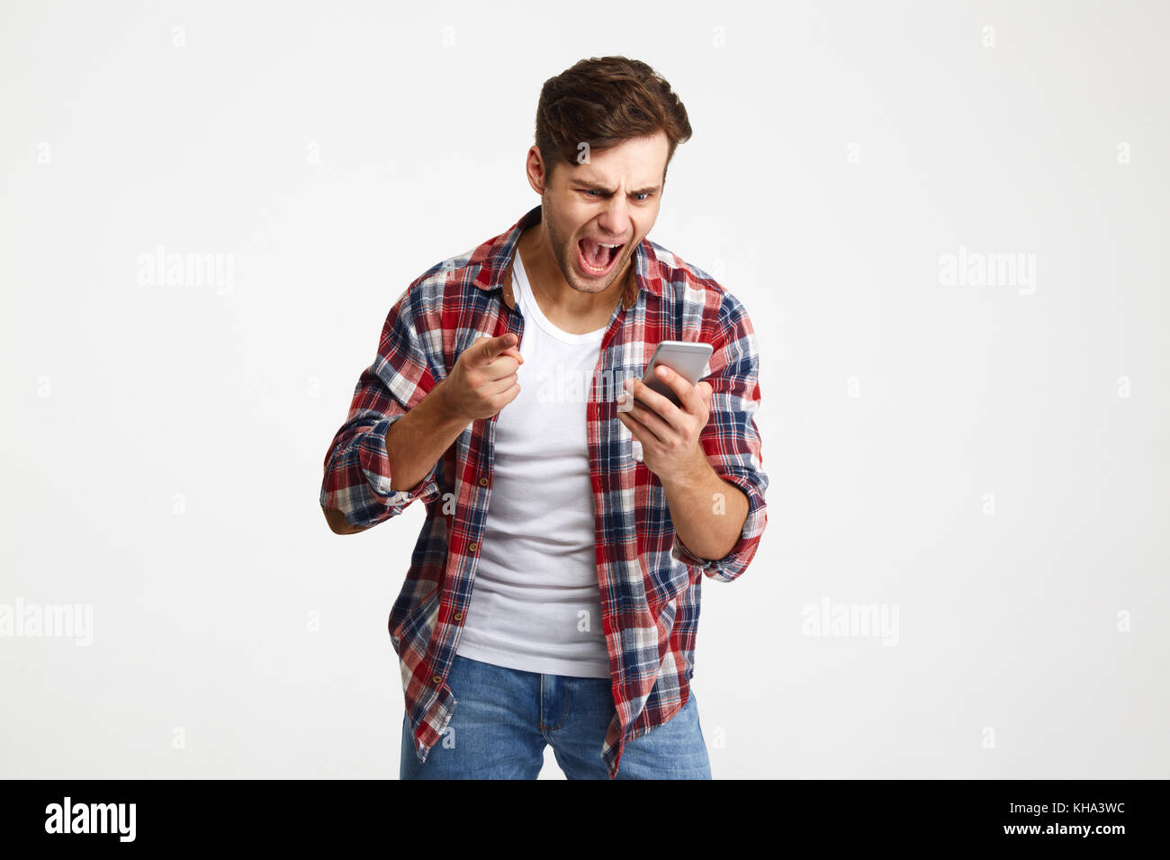Porträt eines zornigen unzufrieden Mann an Handy suchen und schreien auf weißem Hintergrund Stockfoto