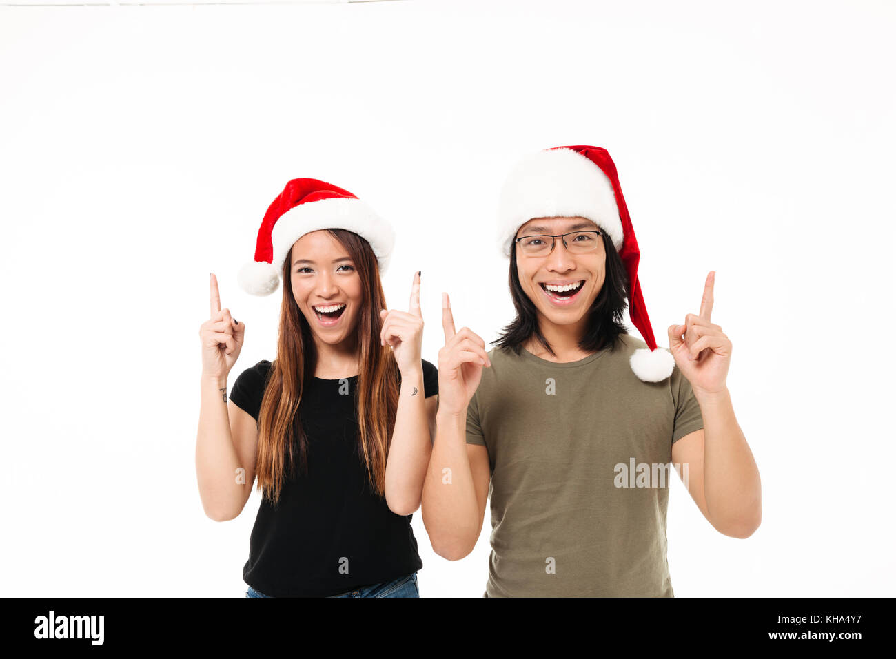 Portrait eines glücklichen asiatischen Paar in Weihnachten hüte Pointing Finger auf Platz kopieren, und wenn man die Kamera auf weißem Hintergrund Stockfoto