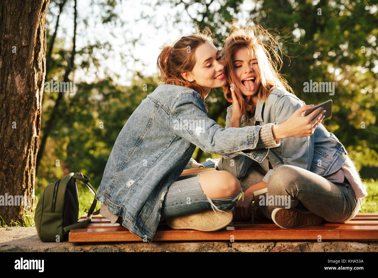 Nahaufnahme von zwei brünette jugendlich Mädchen in Jeans Jacke Spaß während der Einnahme von selfie auf Handy im Park im Freien Stockfoto