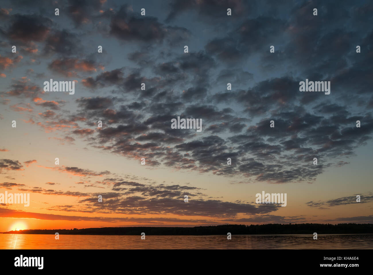 Schöne orange Sonnenuntergang über dem Fluss mit der Sonne und Wolken im Wasser spiegelt Stockfoto