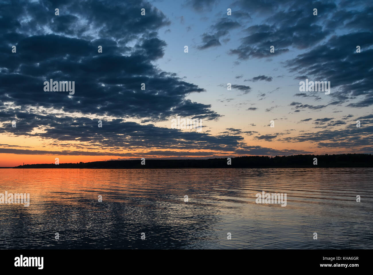 Schöne orange Sonnenuntergang über dem Fluss mit der Sonne und Wolken im Wasser spiegelt Stockfoto