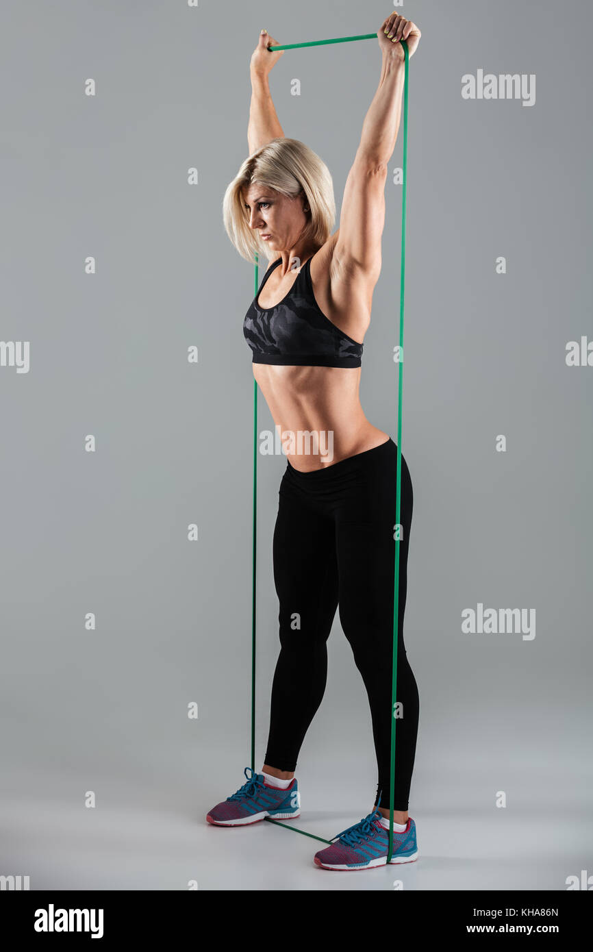 Seitenansicht Foto von gesunden Sport Frau mit erhobenen Armen stretching mit elastischem Gummi, auf weißem Hintergrund Stockfoto
