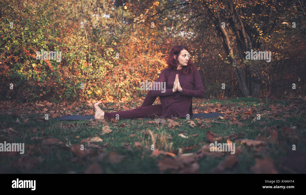 Mädchen auf einen Herbst Tag Üben Yoga im Freien, Ardha Matsyendrasana (halbe Herr der Fische, vakrasana oder die Hälfte der Wirbelsäule verdrehen), Arme vor Stockfoto