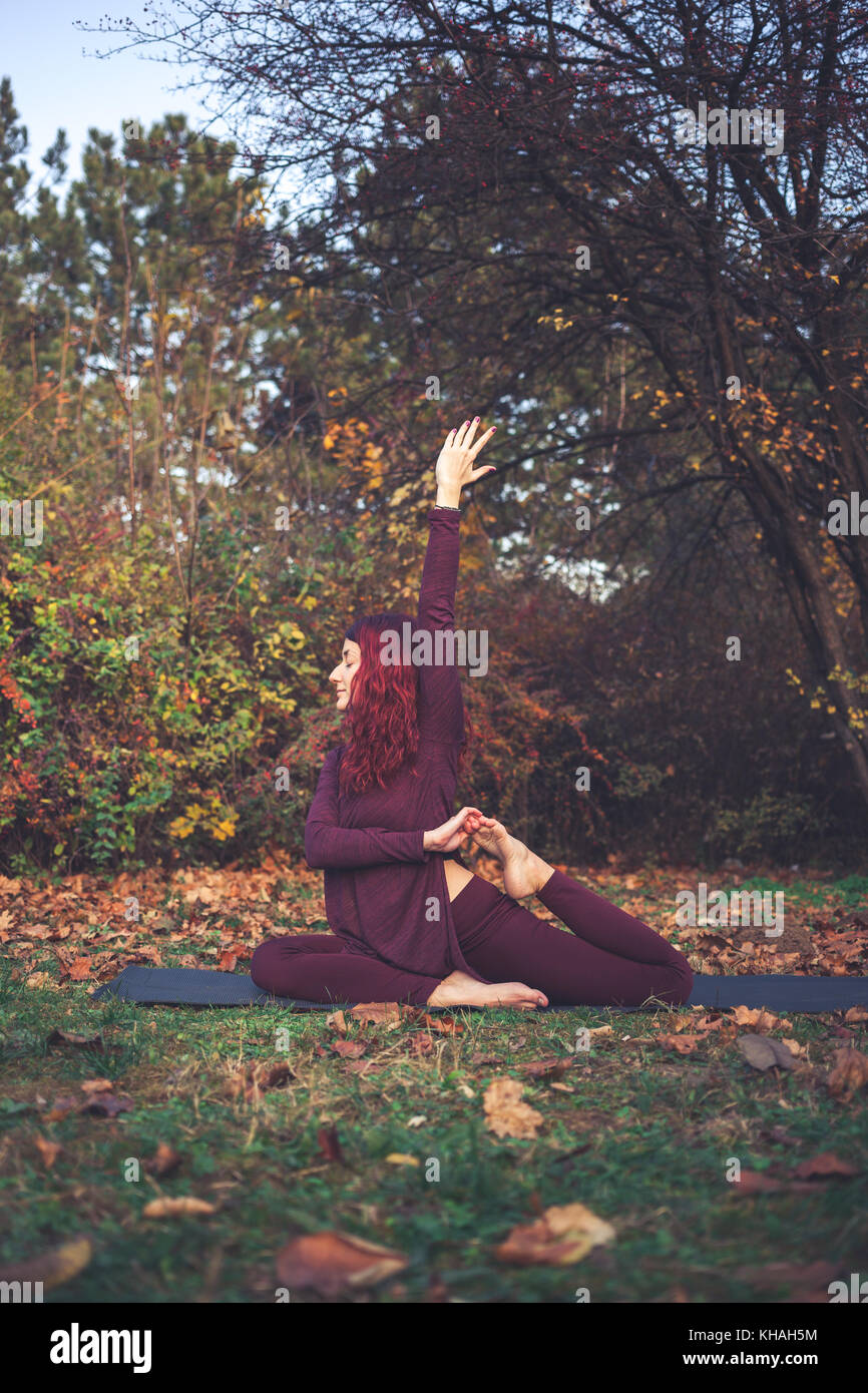 Mädchen an einem strahlenden Herbsttag Yoga im Freien, eine Variation auf Einbeinige König Taube (Eka Pada rajakapotasana) Stockfoto