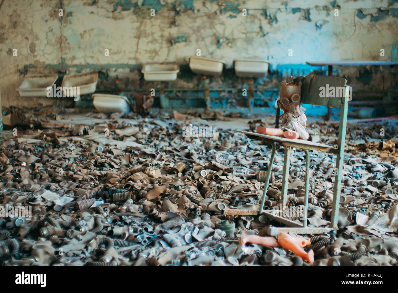 Ein Kind Puppe ist Aufgestützt auf einen Stuhl in einem Meer von Kinder- und Gasmasken Überbleibsel aus dem Kalten Krieg in einer verlassenen Schule in Pripyat, Tschernobyl Stockfoto