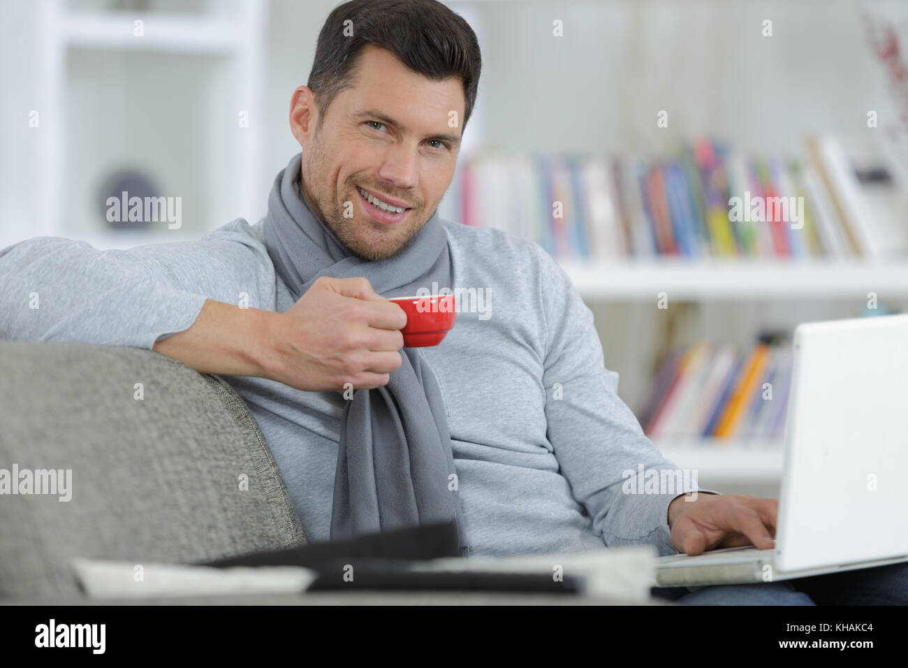 Schöner mann Kaffee trinken während der Arbeit mit dem Laptop zu Hause Stockfoto