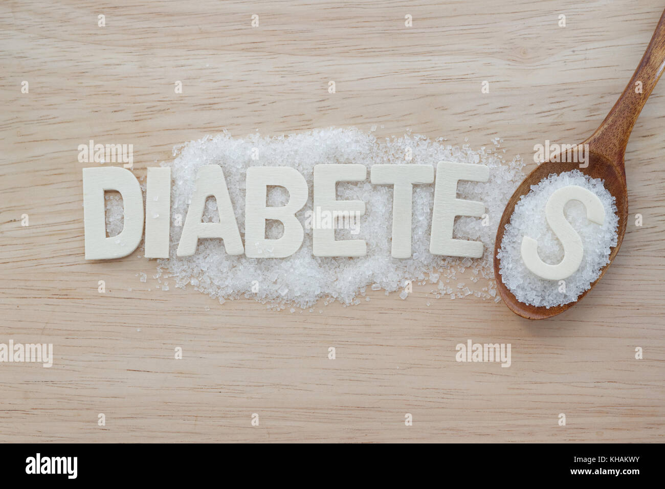 Diabetes Konzept. Alphabet mit Wort Diabetes mit Zucker und Löffel aus Holz auf Holz- Hintergrund. aphabet s auf Haufen Zucker in Löffel aus Holz. Stockfoto