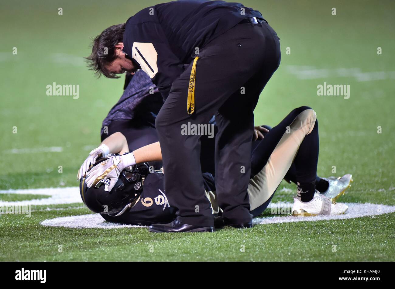 Verletzte Fußballspieler auf dem Feld durch die Schulung von Mitarbeitern bei einem High School Spiel behandelt. USA. Stockfoto