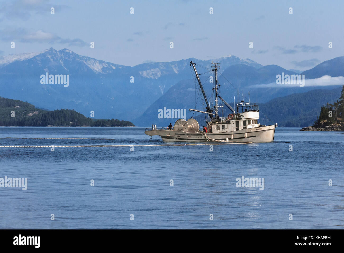 Fischer auf der kanadischen Schiff bin arinet' eher seine Netz während eine kommerzielle Lachsfang in der Johnstone Strait, BC (Coast Range im Hintergrund). Stockfoto
