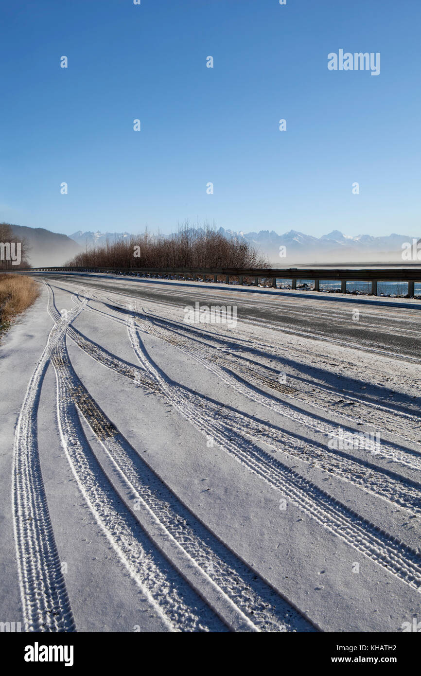 Reifen Spuren im frischen Schnee früh im Winter in einem ausziehbaren auf einer Autobahn in Southeast Alaska am Chilkat River. Stockfoto