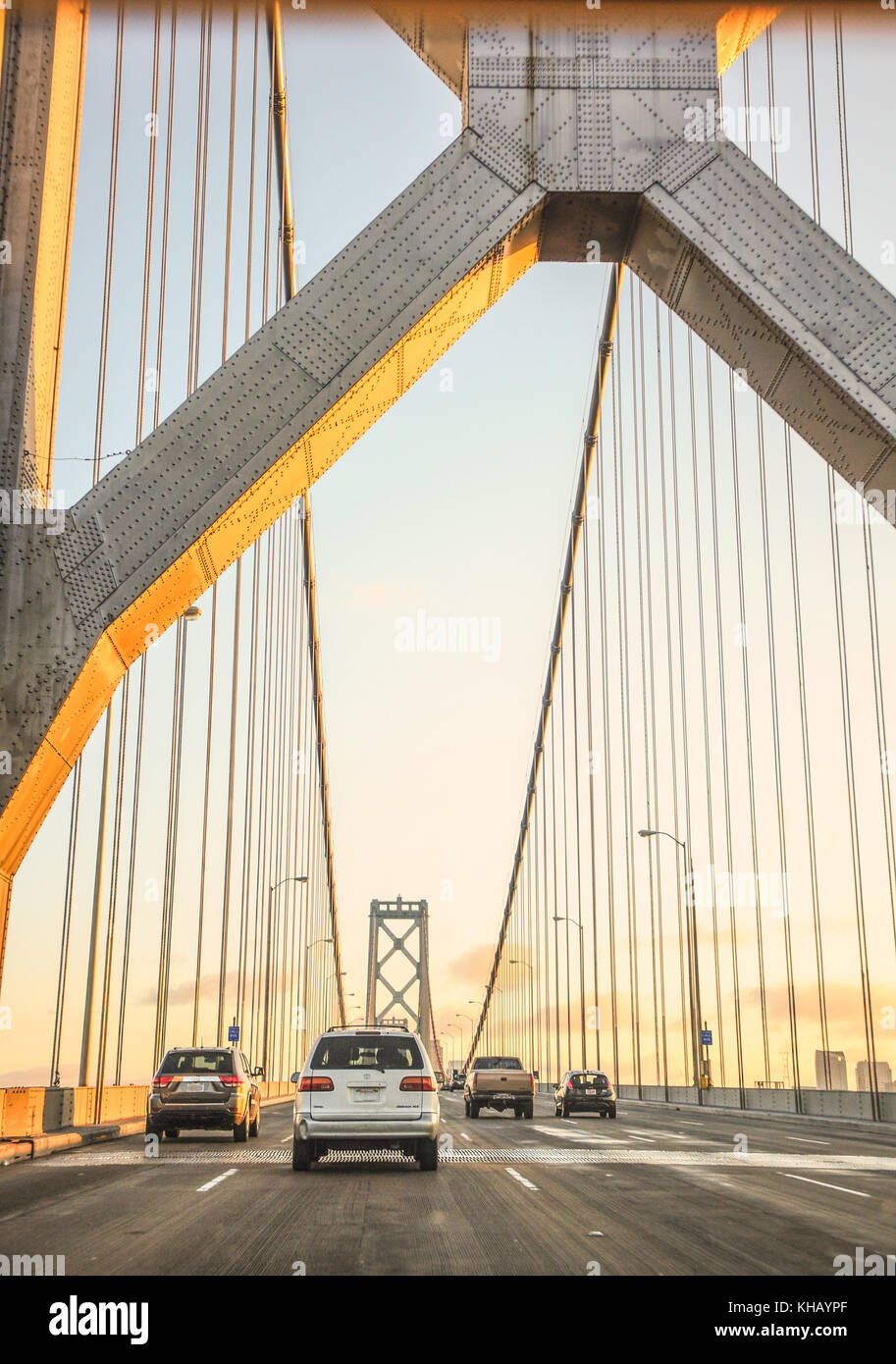 Die Bay Bridge erleuchtete bei Sonnenuntergang, während Autos von der Ostbucht über die Bay Bridge nach San Francisco fahren. 260.000 Menschen überqueren jeden Tag Stockfoto