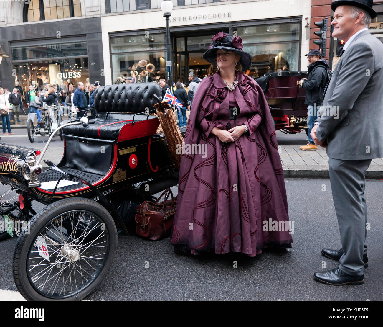 Ein paar in historischen Kostümen vor, die neben einem 1903 Oldsmobile, in der bonham Veteran Car Zone des 2017, Regents Street Motor Show. Stockfoto