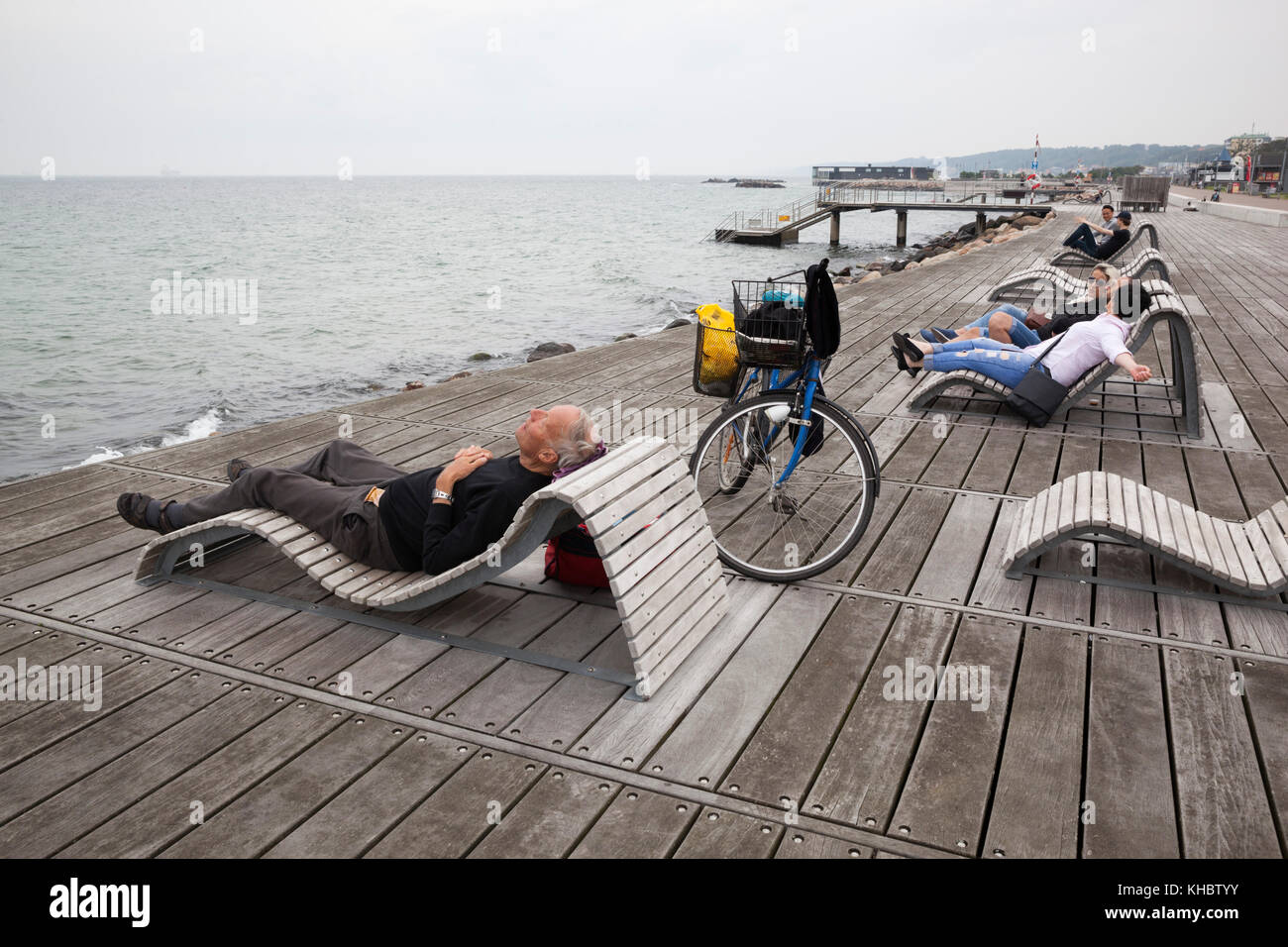 Menschen entspannen auf Liegestühlen neben der Meerenge von Oresund im Park Groningen, Helsingborg, Scania, Schweden, Europa Stockfoto