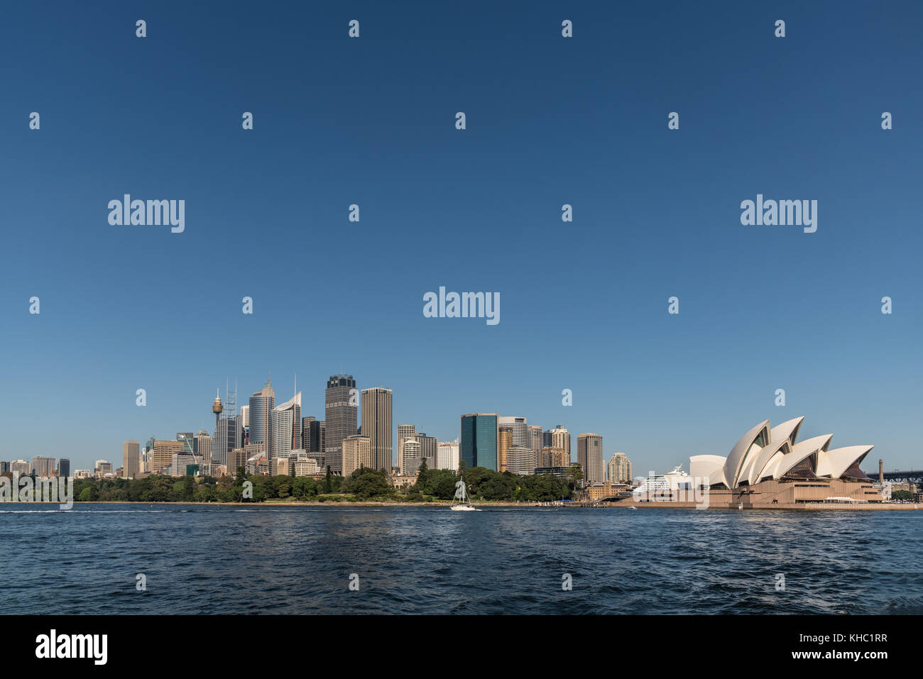 Sydney, Australien - 26. März 2017: Kombination von tall office towers Skyline und das berühmte Opernhaus aus gesehen das Wasser unter blauen Himmel. Kleine whit Stockfoto