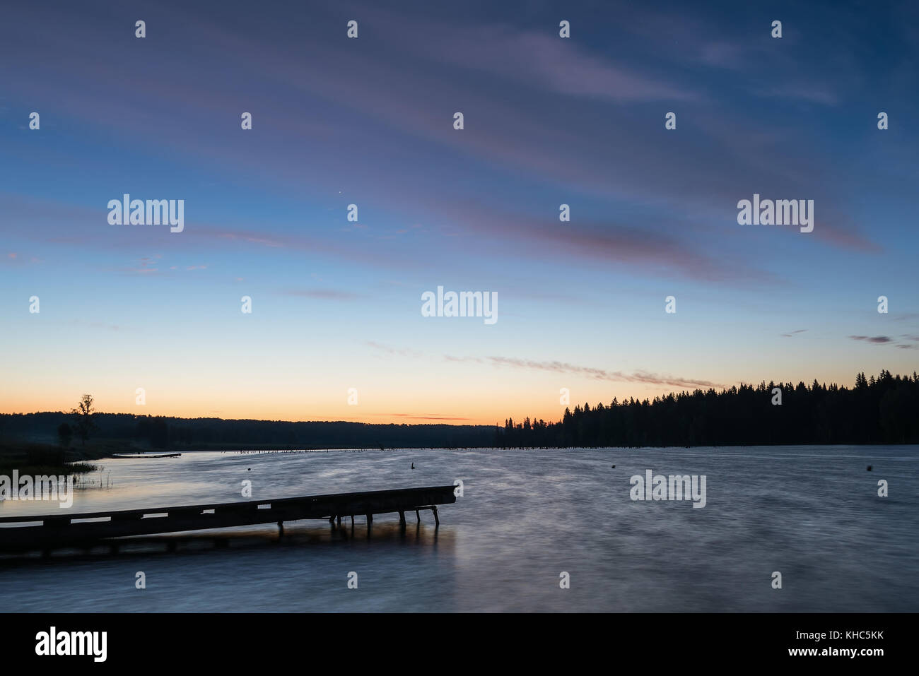 Malerische orange und blau Sonnenuntergang am See mit Wolken im Wasser spiegelt, Schuß auf eine lange Belichtung Stockfoto