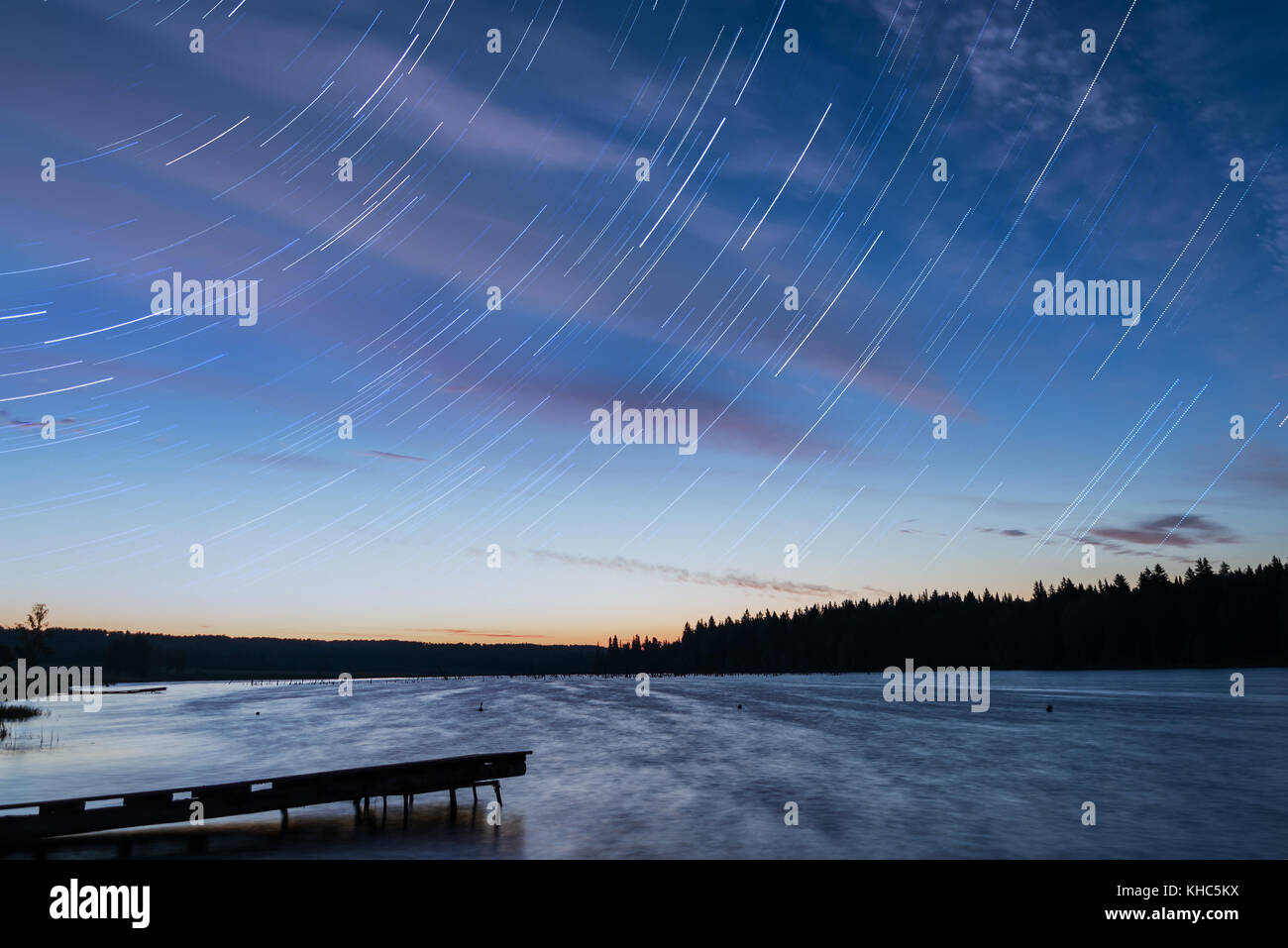 Malerische orange und blau Sonnenuntergang am See mit Sternschnuppen in Form von Tracks, Schuß auf eine lange Belichtung Stockfoto