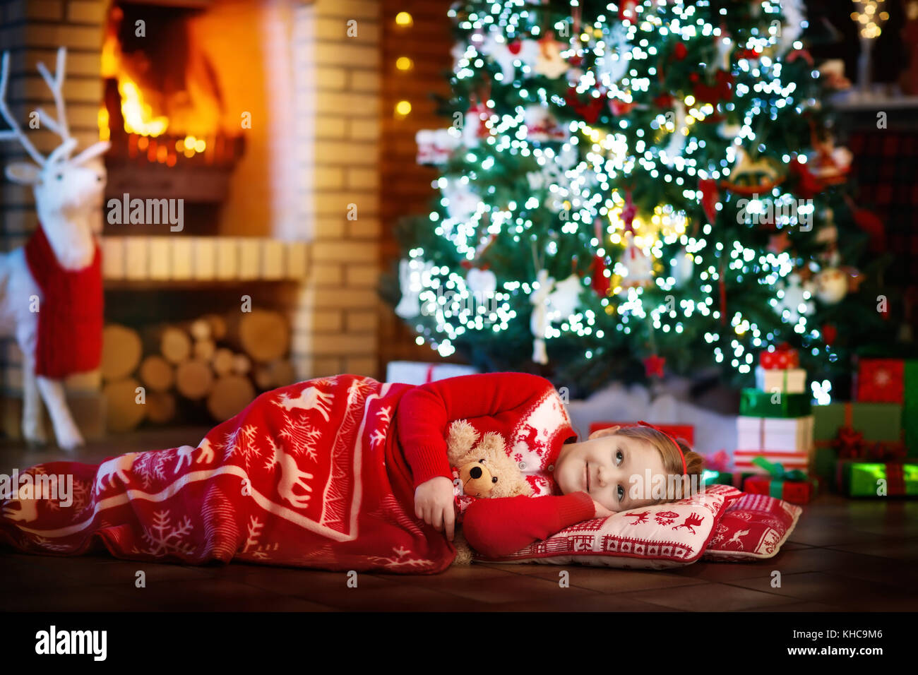 Kind Schlafen am Kamin am Heiligabend unter dem geschmückten Baum. Familie Weihnachten zu Hause feiern. Kinder schlafen. präsentiert auf der Kamin. Wenig g Stockfoto
