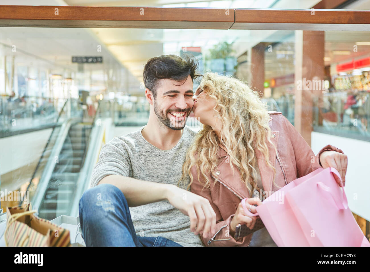 Junge Frau küsst ihr Freund beim Einkaufen und Dank für ein Geschenk Stockfoto