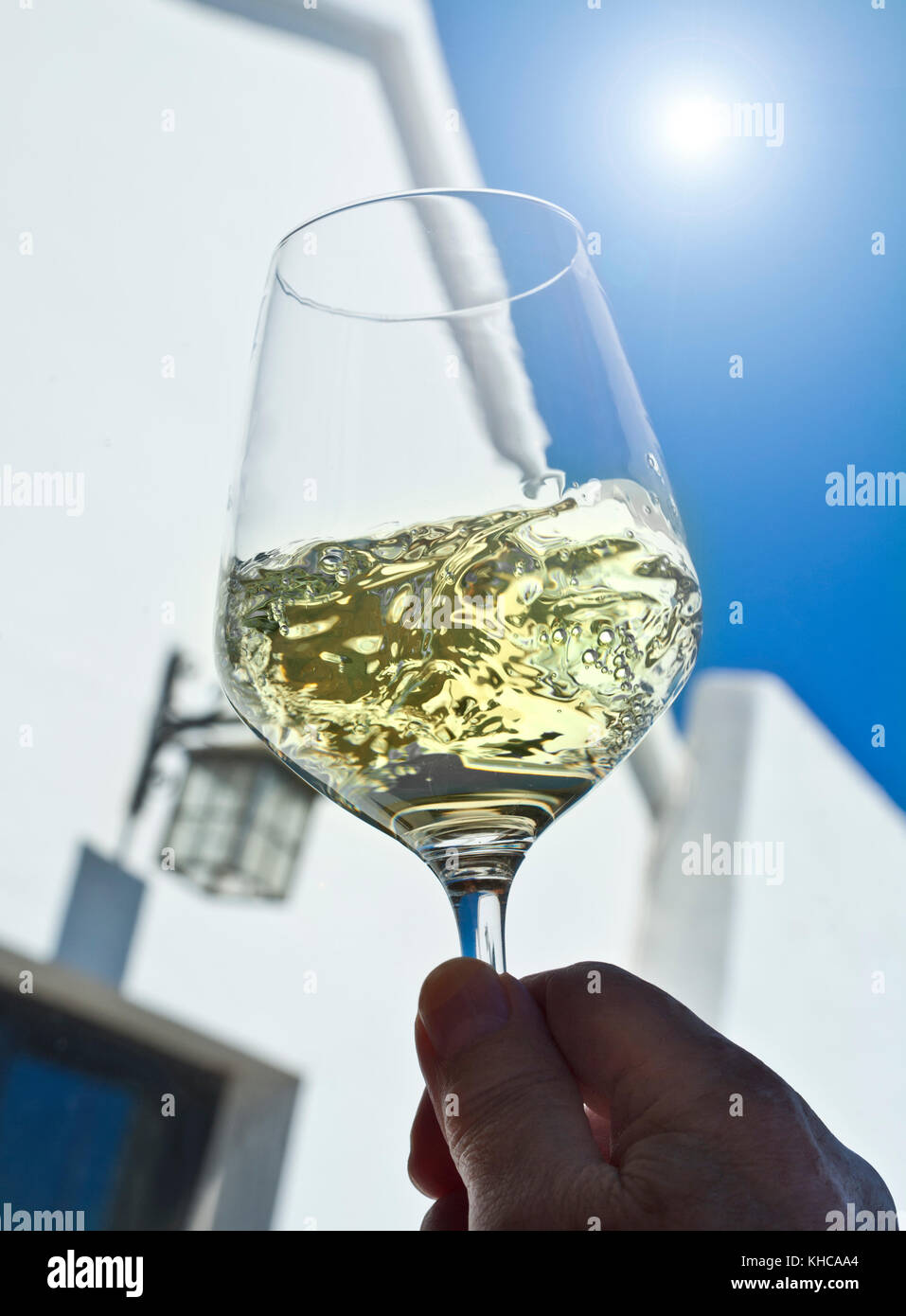 Weißwein Sonne, Glas wirbeln Verkostung und Bewertung in sonnigen blauen Himmel im Freien draußen Wein trinken Probe Terrasse Situation Stockfoto